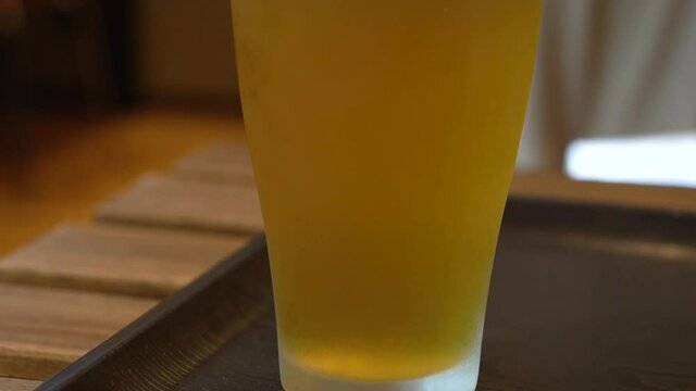 Freshly brewed, cold beer pint with no froth. served in a large glass container. close up establishing shot.