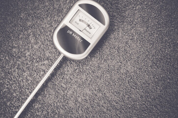 Grayscale shot of analog tool to measure soil on a rough textured background