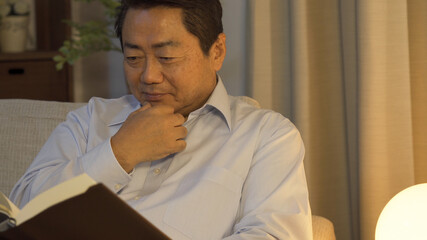 Fototapeta premium 夜間に読書をする中高年男性