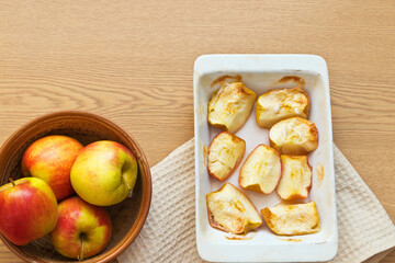Naklejka na ściany i meble Freshly baked sweet apples in ceramic form on a wooden table. Delicious organic sweets rich in fiber. Digestible food for elderly people, children and people with health problems. Flat lay, copy space