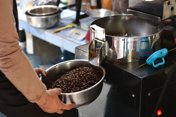 Close up professional coffee roaster holding bowl with beans. Control concept