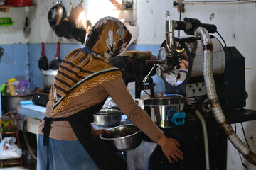 A female coffee roaster is roasting coffee beans using a roasting machine