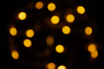 Defocused gold small bokeh on a black background. abstract background. Christmas bokeh yellow.