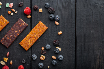 Fruit berry and nut energy bars, healthy snack, top view with copy space, on black wooden table