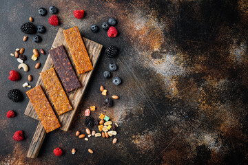 Fruit berry and nut energy bars, healthy snack, flat lay with space for text, on old dark table