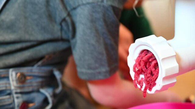 Focus on cranberry food processer with blurred background of young children helping to cook