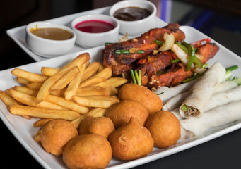 Sharing platter with chicken balls, beef tortilla wraps, chili rips, French fries and sauces