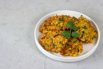 Perkedel jagung or bakwan jagung, corn fritters with chili sauce served on a plate. Indonesian cuisine.