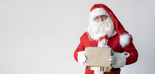 Santa Claus is holding a box with a gift in craft paper. It stands near the space for the text.
