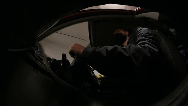 Man In Protective Face Mask Driving Car in Underground Garage Interior POV