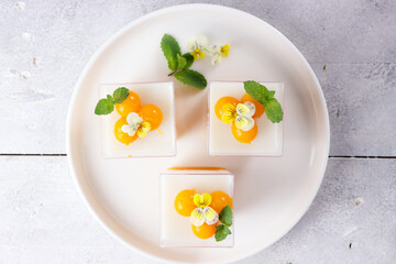 Puding mangga or Homemade fresh mango jelly and coconut pudding decorated with mint and viola edible flowers.
