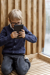 blond boy with glasses looking enthusiastically at the tablet computer