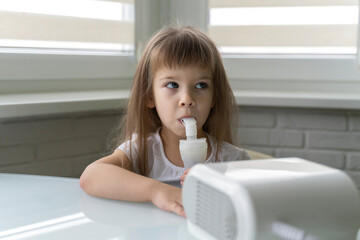 cute little girl uses nebulizer at home. treatment of bronchitis and asthma with inhalation