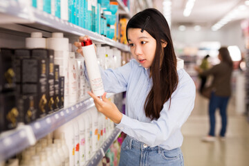 .Asian woman customer buying shampoo in hair care products shop.