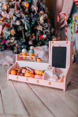 Christmas gifts for kids under the tree. Christmas tree decorated with toys and colorful candy canes and sweets. Present boxes under the christmas tree. Toy coffee shop made of wood.