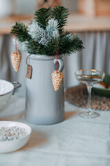 Christmas decorations. Fir branches with snow inside the vase on the christmas table. Decoration of festive table for christmas eve. Festive dish for new year eve.