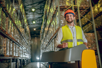 Warehouse worker in orange helmet working and smiling
