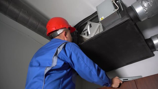 Skilled specialist inspecting filter of central air ventilation system device
