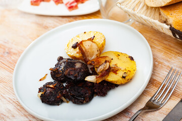 Blood sausage black pudding served with boiled potato and fried onion