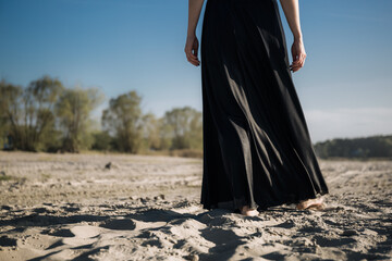A woman walks into the distance on the sand with her bare feet. Black and white photo of a part of...