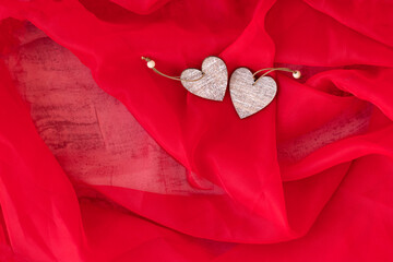Two wooden hearts on red textile background. Romantic gift for Valentine's day. Love and romantic concept. Soft focus. Copy space.