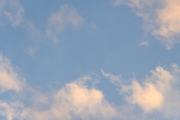Colorful blue sky and clouds highlighted by setting sun, as a nature background
