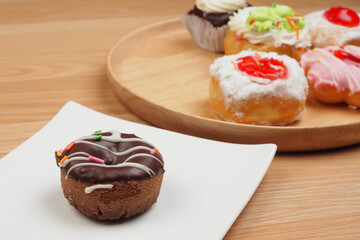 Tasty donut in white dish on brown wooden table background, bakery