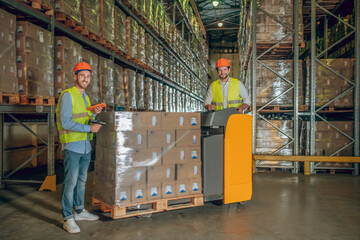 Male warehouse workers in helmet scanning barcodes on the boxes