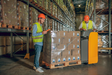 Male warehouse workers in helmets standing near containers