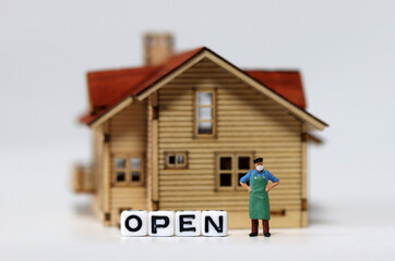 Close-up on a 'OPEN' and a miniature man wearing a mask. The concept of stores that are starting to reopen as the Corona continues.
