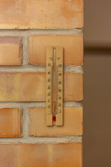 Wooden thermometer on a brick wall