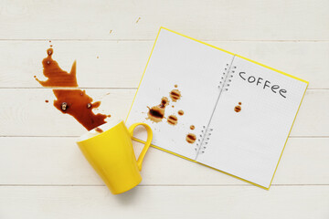 Overturned cup of coffee on wooden background