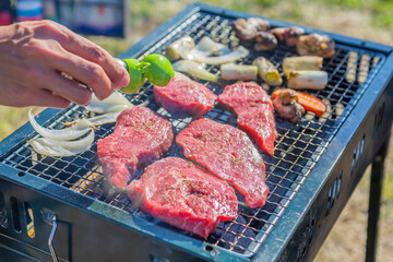 屋外のオープングリルで牛肉を網焼きしている様子