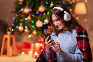 Beautiful young woman listening to Christmas music at home