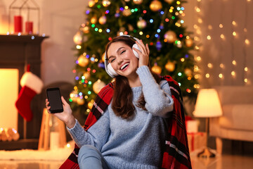 Beautiful young woman listening to Christmas music at home