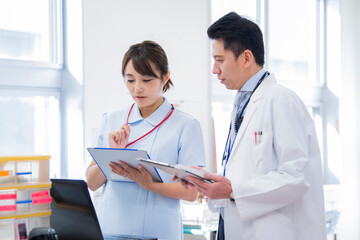ナースステーションで笑顔で会話をする医師と看護師