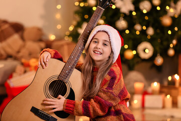 Cute little girl with guitar at home on Christmas eve