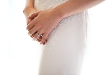 Closeup hands of bride resting on her wedding dress