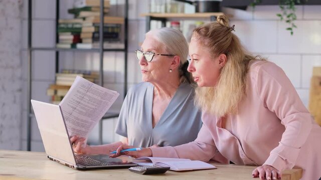 Woman teaching senior mother to use internet at home. Senior woman with her daughter looking at modern gadget indoors. close up view. Slow motion nvideo. stock footage