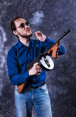 Mature man in sunglasses with tommy gun