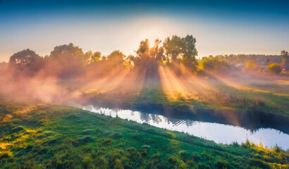 Awesome summer sunrise on the foggy river. Incredible morning scene with first sunlight, Ternopil region, Ukraine, Europe. Beauty of countryside concept background.