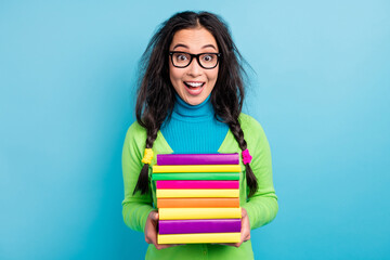 Photo of positive amazed shock young woman hold textbooks wear green shirt isolated on vivid blue color background