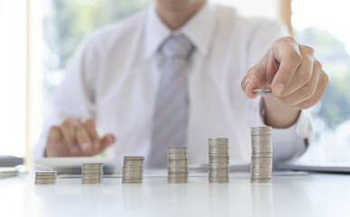 Businessman putting money on stacking coin that shows a graph the financial growth profit of...