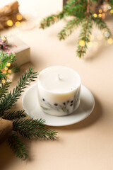 Trendy handmade soy candle, natural decorations, gingerbread cookies on beige background. Christmas zero waste eco friendly gift concept.