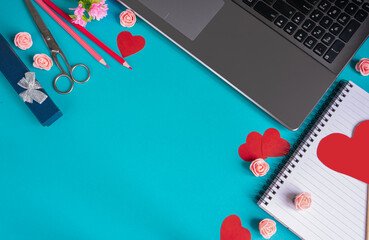 The background of Valentine's day. Empty blank Notepad, laptop, pencils, scissors, red hearts on a blue background. Valentine's day greeting card concept. Flat layout, top view, copy space