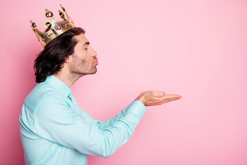 Photo portrait profile of guy in crown sending air kiss with two hands isolated on pastel pink...