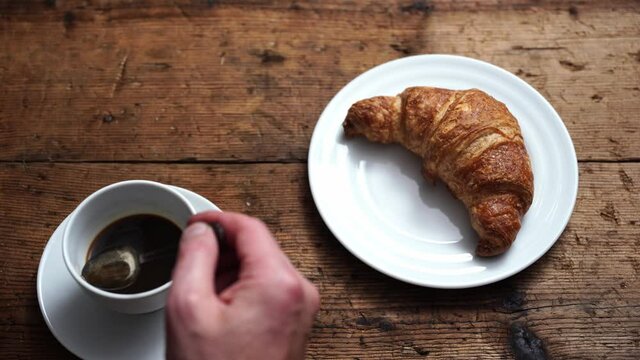 have breakfast with coffee and croissants. bring a croissant to your mouth