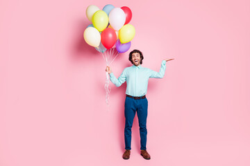 Fototapeta na wymiar Photo portrait full body view of man holding blank space in hand with air balloons isolated on pastel pink colored background