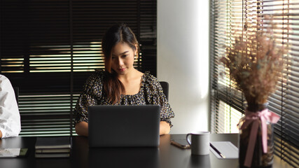 Businesswoman working with laptop in modern meeting room
