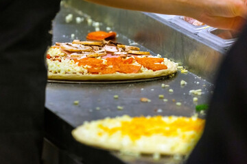 Cook in the kitchen putting the ingredients on the pizza. Production and delivery of food.